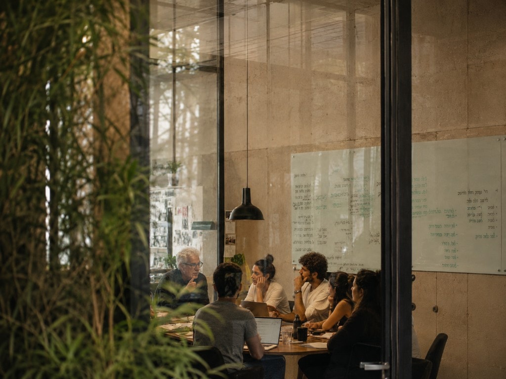 A team gathered around a table in a workshop, in conversation